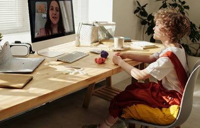 A person sitting at a table with a laptop and a computer.